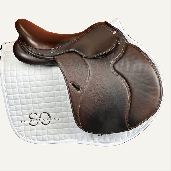 Brown saddle on a white saddle pad with 'Saddles Online' branding against a brick wall.