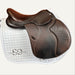Brown saddle on a white saddle pad with 'Saddles Online' branding against a brick wall.